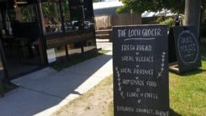 an outdoor standing with the Loch grocer in the bacground