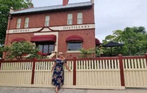 standing out front of the ored brick two story Loch brewery and Distillery