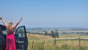 standing on side of car looking at a rural view toward the coastline of Inverloch