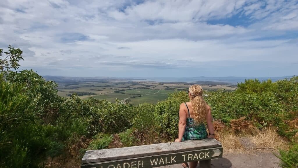 sitting on a seat at Mount Nicoll lookout with sea views and farm land -things to do in Gippsland